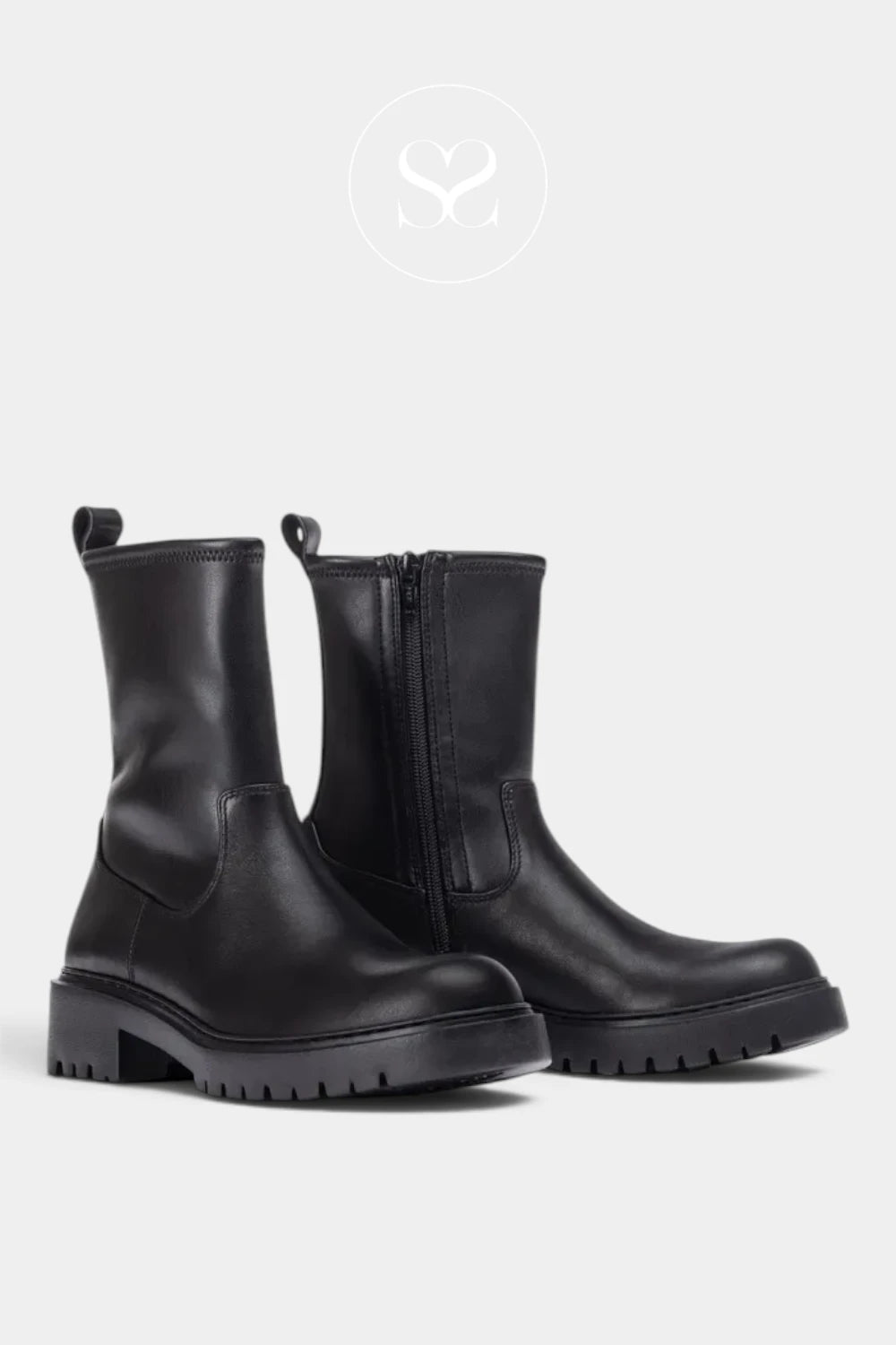 A pair of black leather Chelsea-style ankle boots with side zippers and pull tabs, shown on a light gray background with a faint circular logo above.