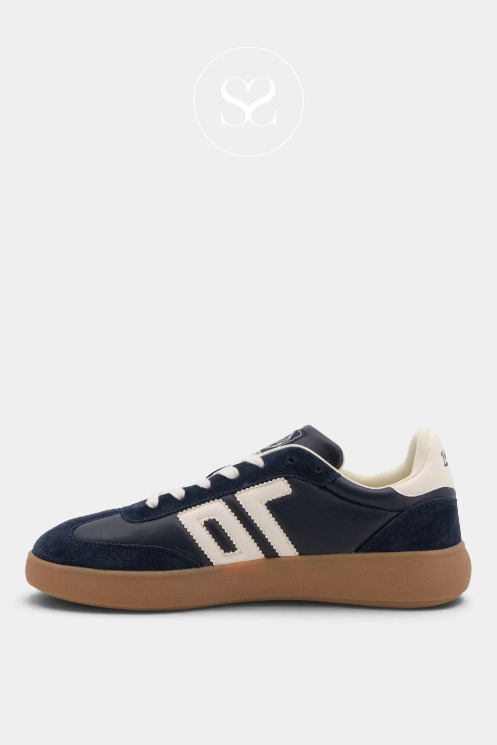 A low-top sneaker in navy blue suede and leather with cream accents, featuring a thick tan gum sole, shown in a side profile on a light gray background.