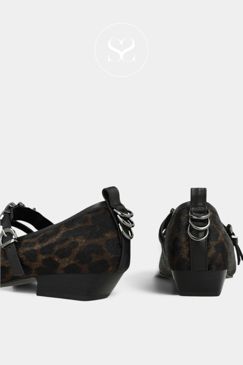 A pair of women's low-heel pumps featuring a brown and black leopard print pattern, black straps, and silver-tone metal hardware, shown from the side against a light gray background.