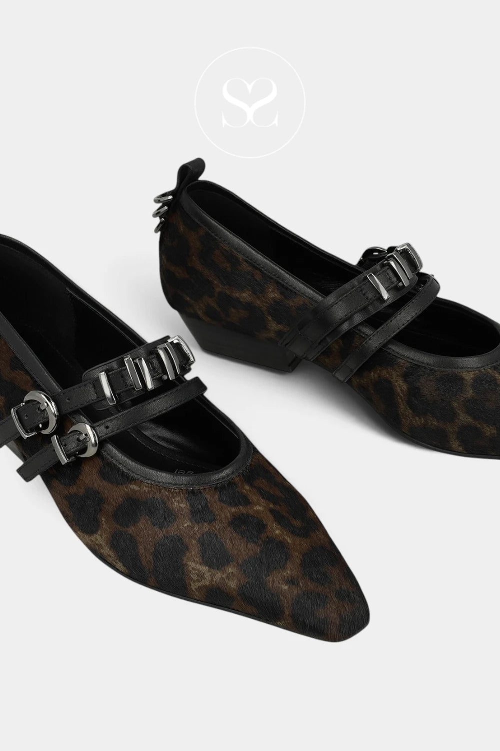 A pair of pointed-toe flats featuring a brown and black leopard print upper with black straps and silver-tone buckle details, displayed on a light gray background.