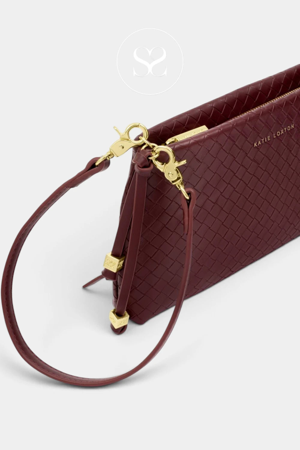 A close-up of a woven leather wristlet clutch in burgundy with gold-tone hardware and a matching wrist strap, shown on a light gray background. The brand name 'Katie Lee Rose' is subtly printed in gold on the side.