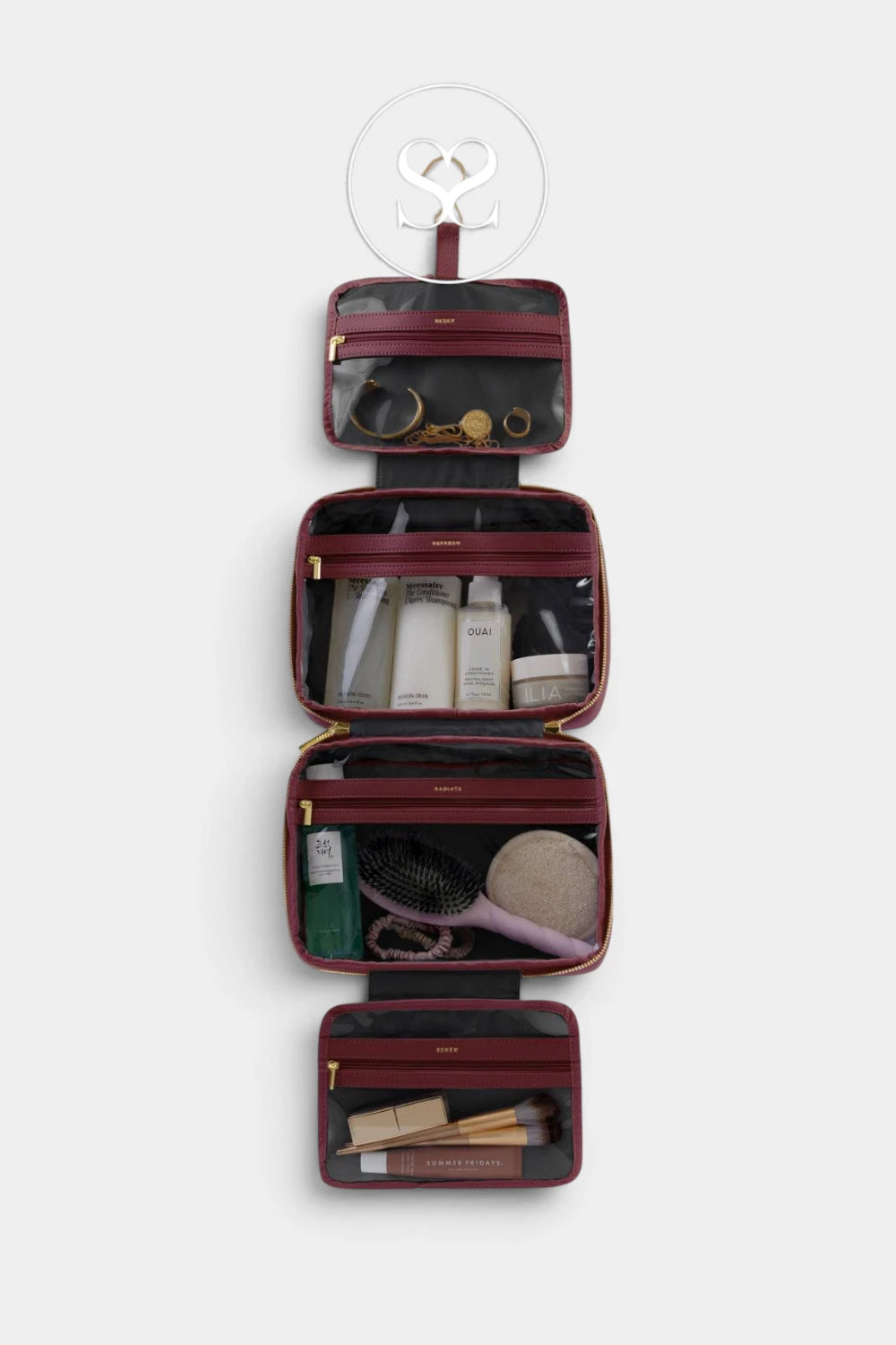 A four-compartment hanging cosmetic bag set in burgundy and black, shown open to display its interior compartments filled with toiletries, against a light gray background.