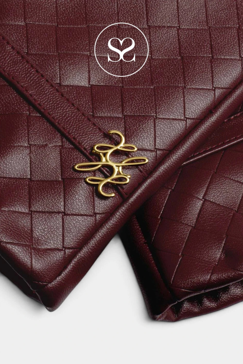 A close-up of a dark burgundy woven leather clutch with a gold-tone interlocking monogram clasp and a white circular 'S2' logo overlay near the top.