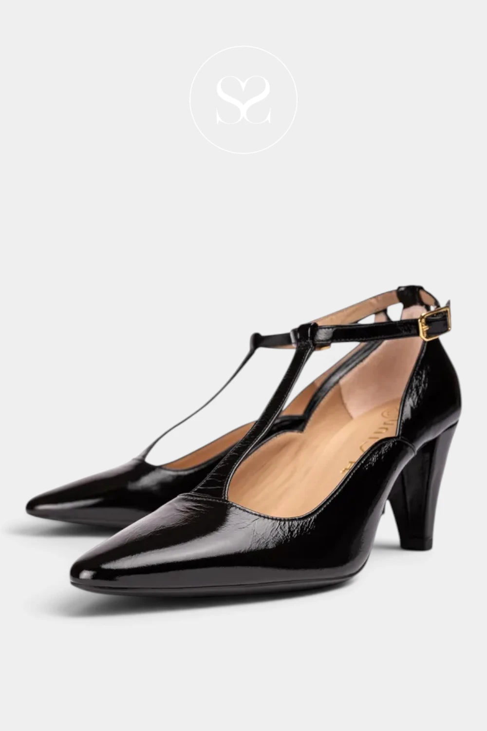 A pair of black patent leather T-strap high heels with pointed toes and block heels, shown on a light gray background with a faint brand logo at the top.