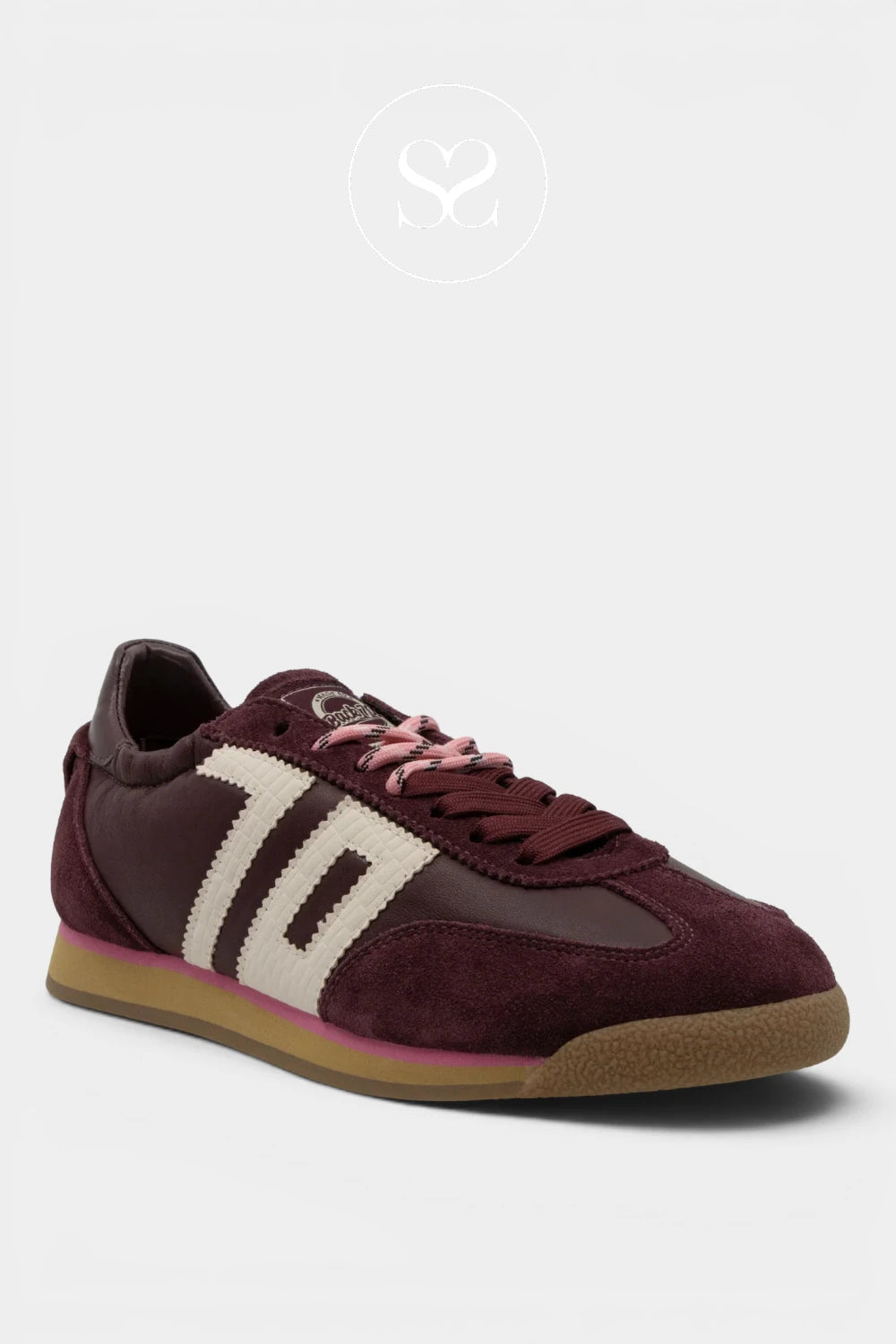 A low-top sneaker in burgundy suede and leather with cream side stripes, pink laces, and a gum sole, shown on a light gray background.