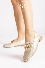 woman wearing gold leather loafers with gold buckle