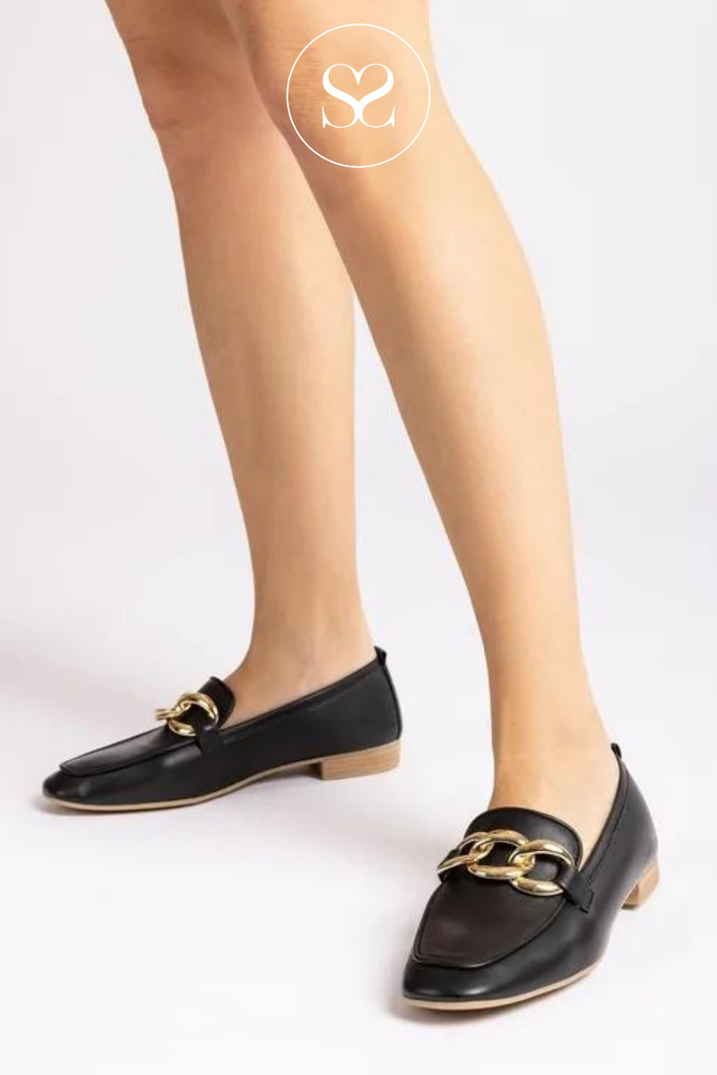woman wearing black leather loafers with low block heel